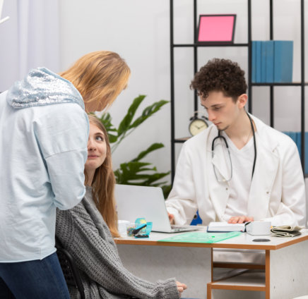 a person sitting at a desk with a doctor and a person looking at her